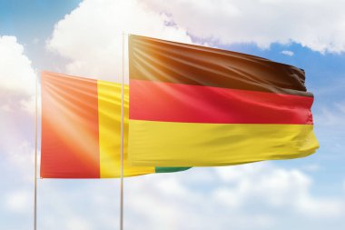 Sunny blue sky and flags of germany and guinea