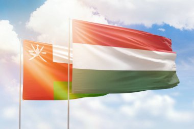 Sunny blue sky and flags of hungary and oman
