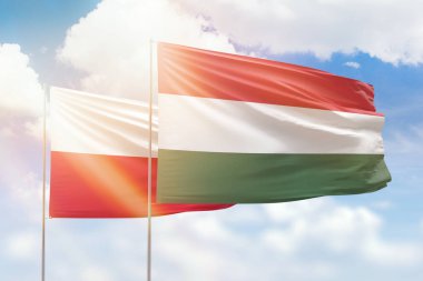 Sunny blue sky and flags of hungary and poland