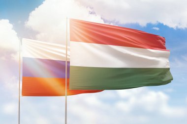 Sunny blue sky and flags of hungary and russia