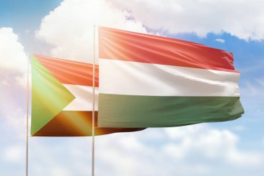 Sunny blue sky and flags of hungary and sudan