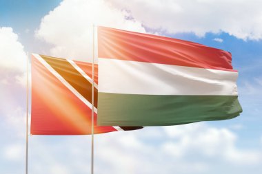 Sunny blue sky and flags of hungary and trinidad and tobago