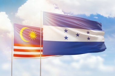 Sunny blue sky and flags of honduras and malaysia