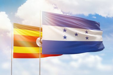 Sunny blue sky and flags of honduras and uganda