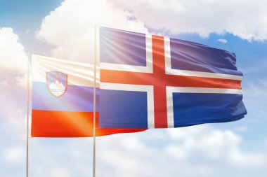 Sunny blue sky and flags of iceland and slovenia