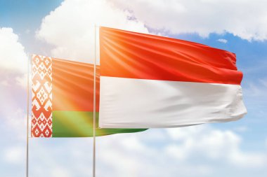 Sunny blue sky and flags of indonesia and belarus