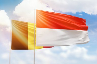 Sunny blue sky and flags of indonesia and belgium