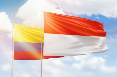 Sunny blue sky and flags of indonesia and colombia