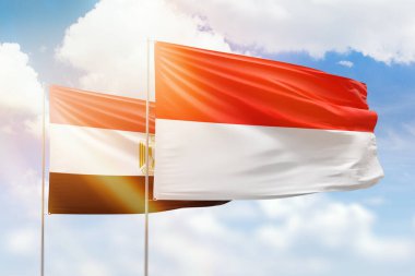 Sunny blue sky and flags of indonesia and egypt