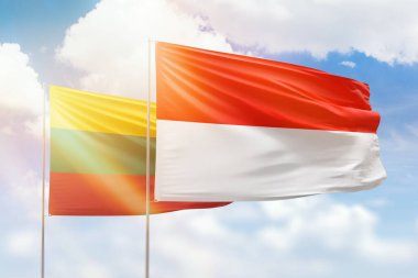 Sunny blue sky and flags of indonesia and lithuania