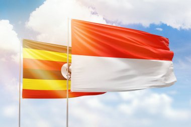 Sunny blue sky and flags of indonesia and uganda