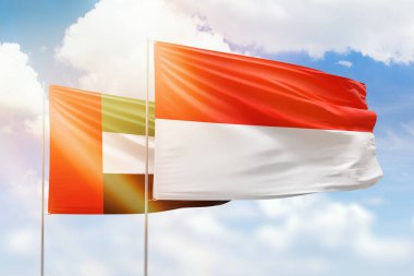 Sunny blue sky and flags of indonesia and uae