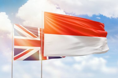 Sunny blue sky and flags of indonesia and united kingdom