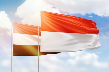 Sunny blue sky and flags of indonesia and yemen
