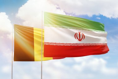 Sunny blue sky and flags of iran and belgium