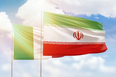 Sunny blue sky and flags of iran and italy