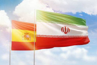 Sunny blue sky and flags of iran and spain