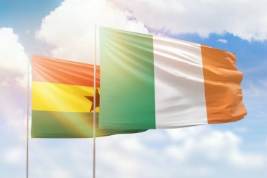 Sunny blue sky and flags of ireland and ghana