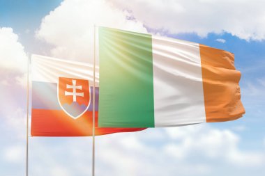Sunny blue sky and flags of ireland and slovakia