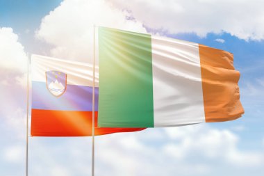 Sunny blue sky and flags of ireland and slovenia