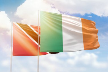 Sunny blue sky and flags of ireland and trinidad and tobago