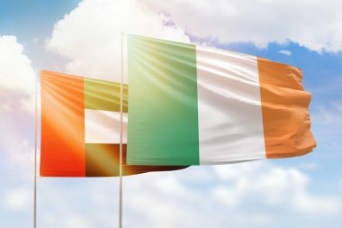 Sunny blue sky and flags of ireland and uae