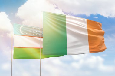 Sunny blue sky and flags of ireland and uzbekistan
