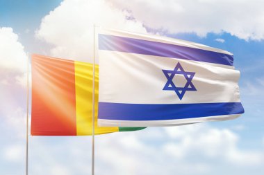 Sunny blue sky and flags of israel and guinea