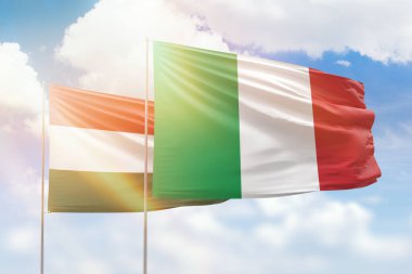 Sunny blue sky and flags of italy and hungary