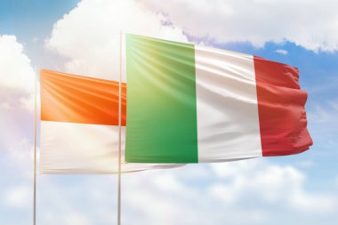 Sunny blue sky and flags of italy and indonesia