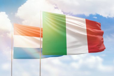 Sunny blue sky and flags of italy and luxembourg