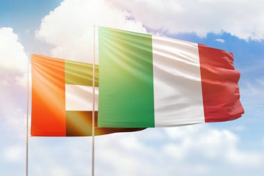 Sunny blue sky and flags of italy and uae