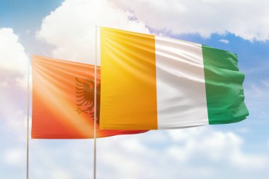 Sunny blue sky and flags of ivory coast and albania