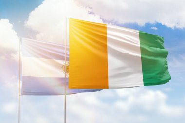 Sunny blue sky and flags of ivory coast and argentina