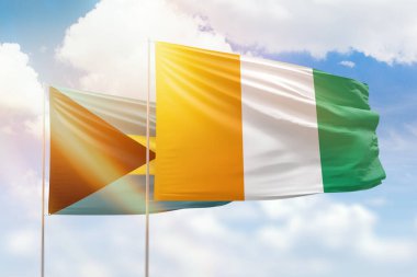 Sunny blue sky and flags of ivory coast and bahamas