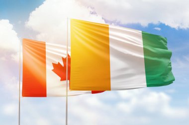 Sunny blue sky and flags of ivory coast and canada