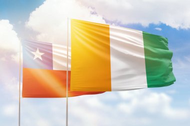 Sunny blue sky and flags of ivory coast and chile