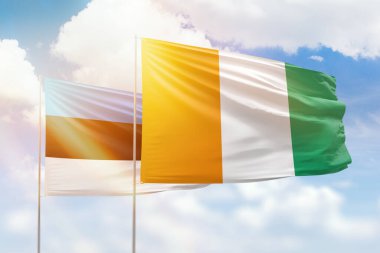 Sunny blue sky and flags of ivory coast and estonia