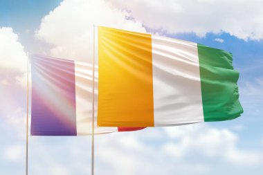 Sunny blue sky and flags of ivory coast and france