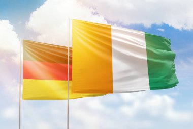 Sunny blue sky and flags of ivory coast and germany