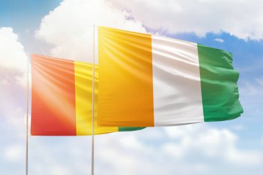 Sunny blue sky and flags of ivory coast and guinea
