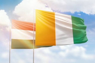 Sunny blue sky and flags of ivory coast and hungary