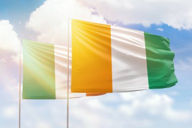 Sunny blue sky and flags of ivory coast and ireland