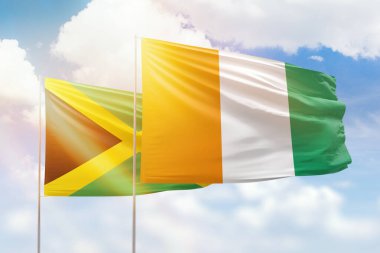 Sunny blue sky and flags of ivory coast and jamaica