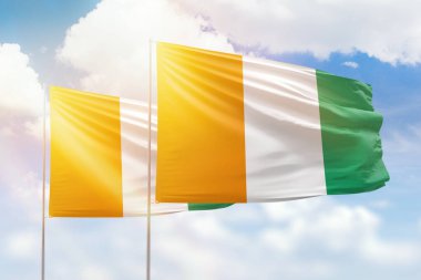 Sunny blue sky and flags of ivory coast and ivory coast