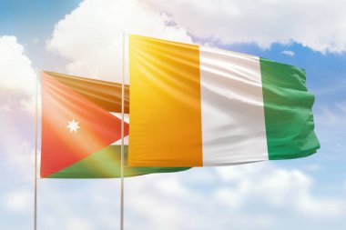 Sunny blue sky and flags of ivory coast and jordan
