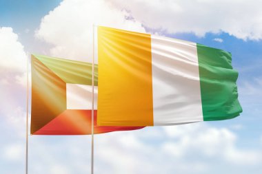 Sunny blue sky and flags of ivory coast and kuwait
