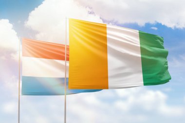 Sunny blue sky and flags of ivory coast and luxembourg