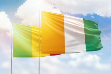 Sunny blue sky and flags of ivory coast and mali