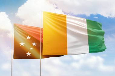 Sunny blue sky and flags of ivory coast and papua new guinea